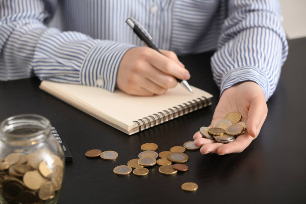 человек считает деньги, разложенные на столе